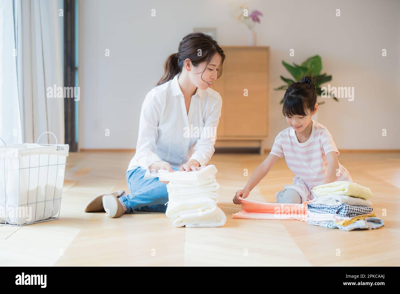 Mother folding laundry with daughter helping Stock Photo Alamy