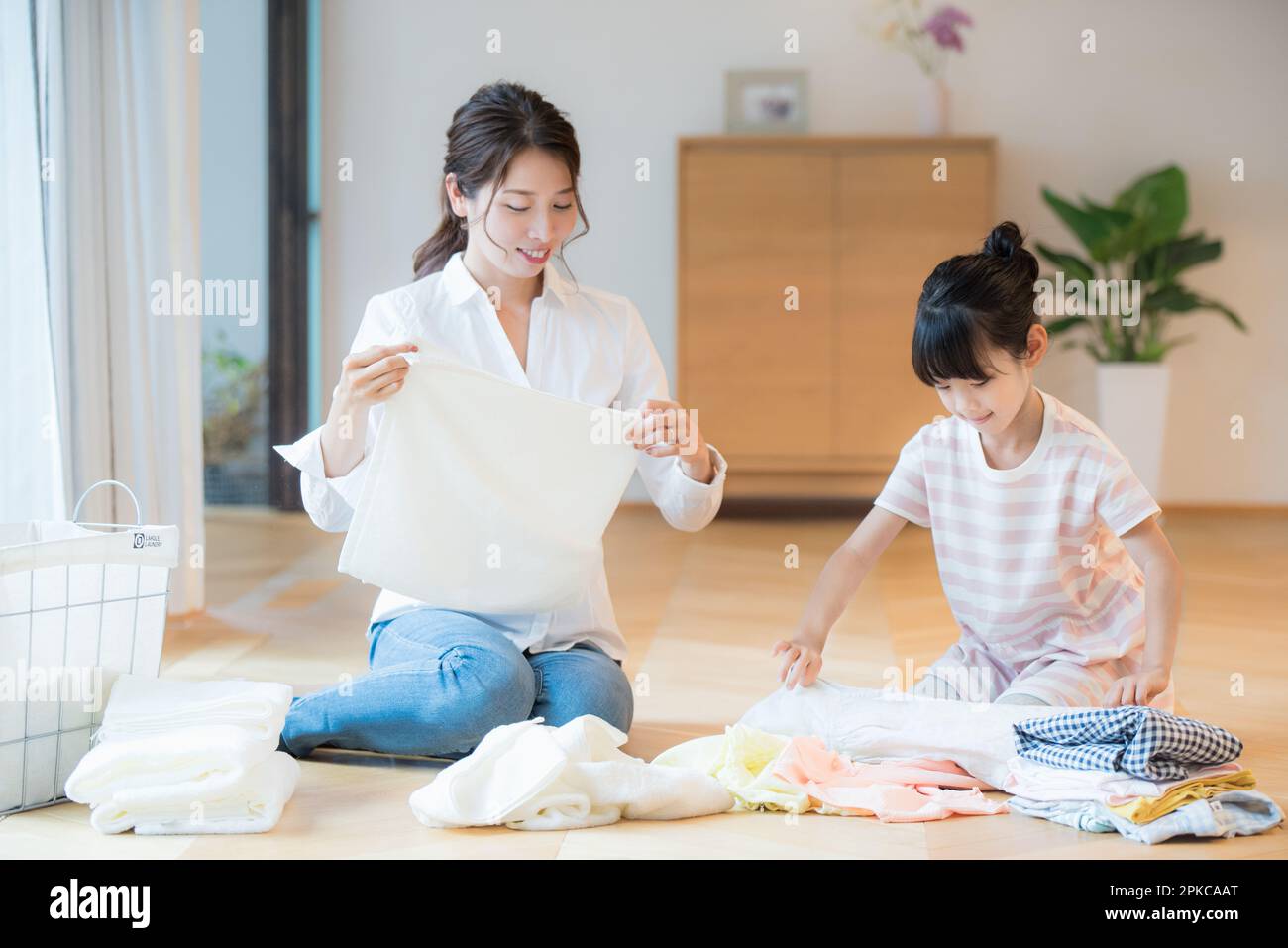 Mother and daughter folding laundry Stock Photo - Alamy