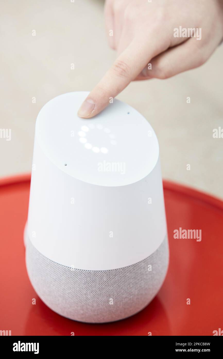 Woman adjusting volume of AI speaker in hand Stock Photo - Alamy