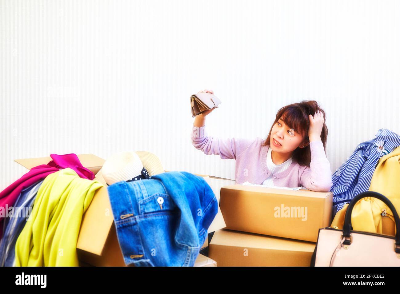 Woman with purse and room cluttered with clothes and bags coming out of boxes Stock Photo