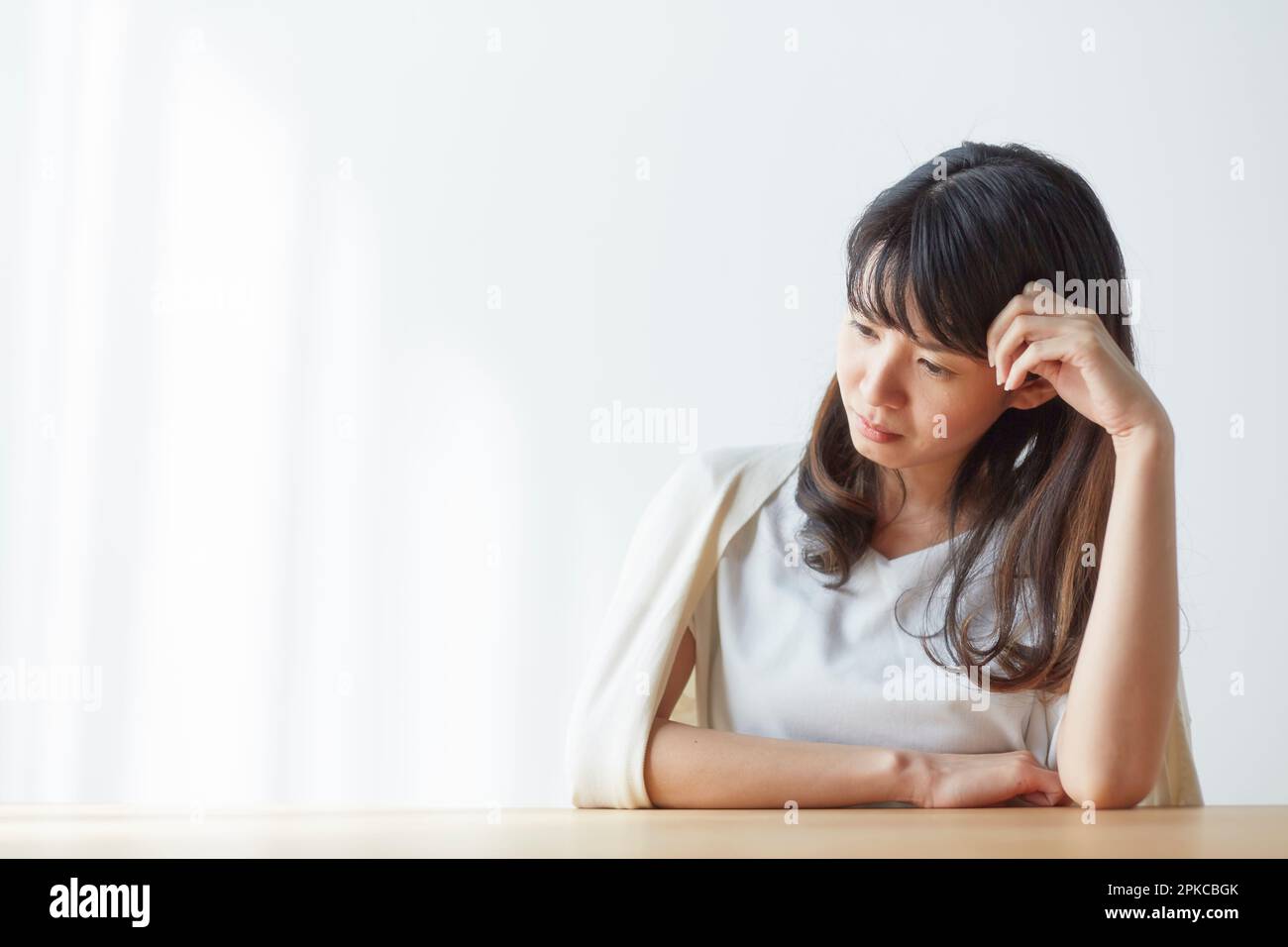 Woman looking down with elbows on table Stock Photo