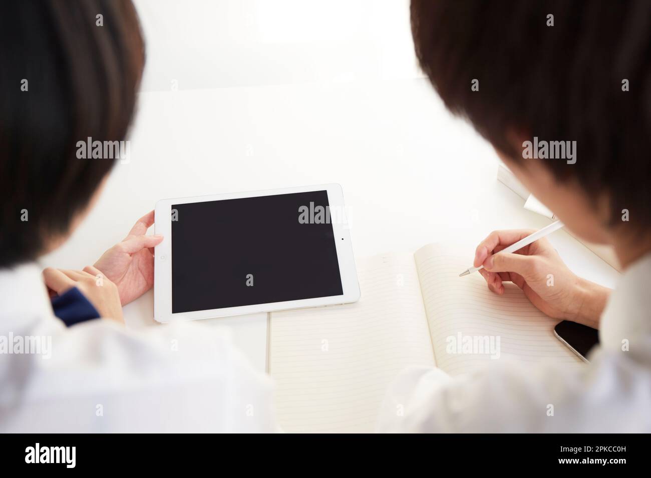 Male and female high school students studying using tablets on their