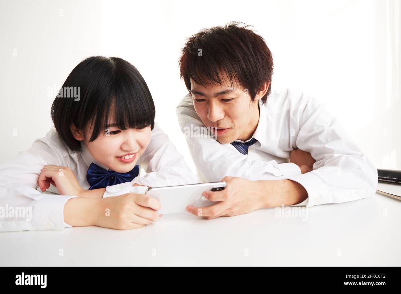 A high school boy and a high school girl looking at their smartphones