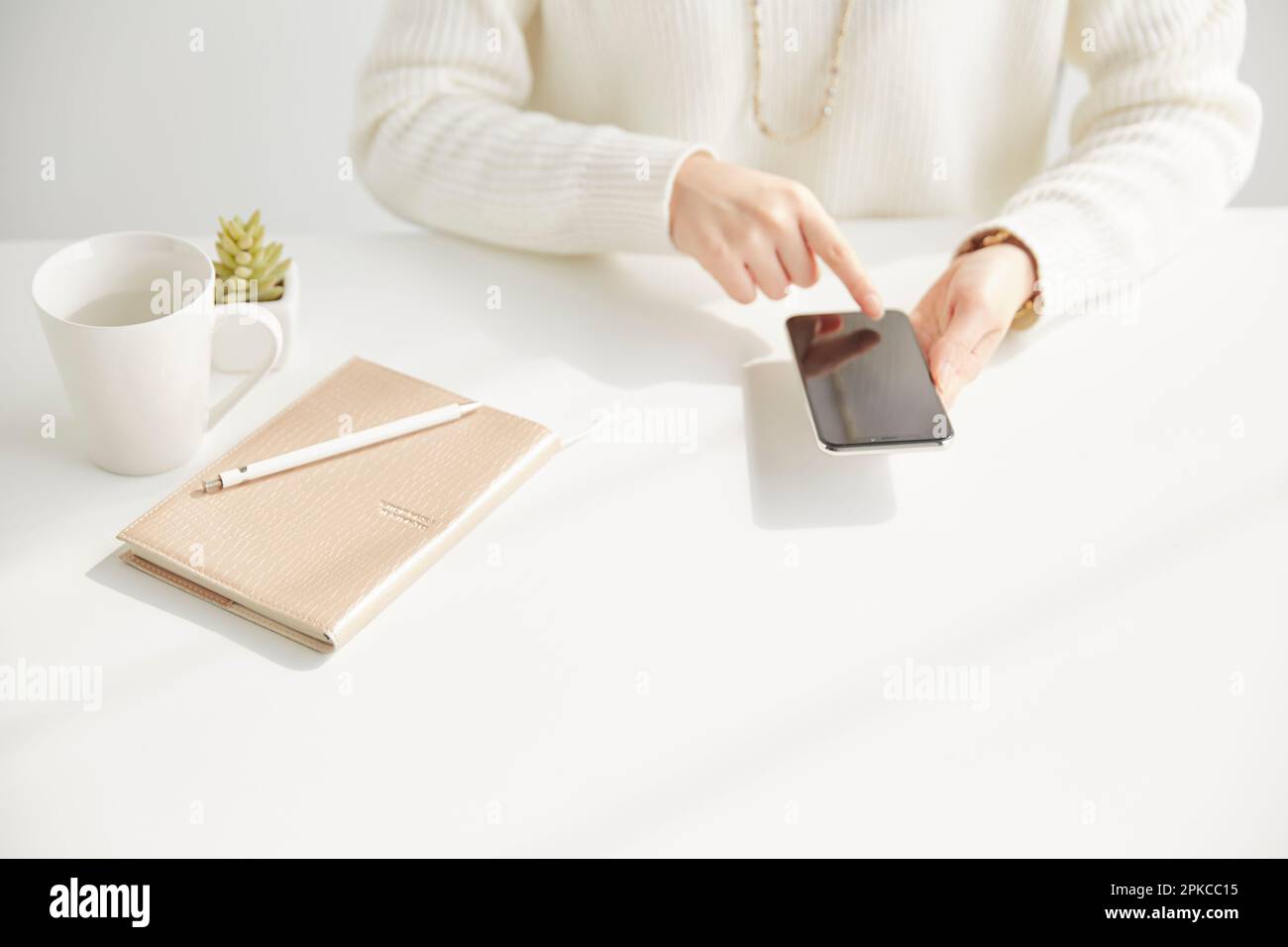 A woman operating a smartphone while sitting at her desk Stock Photo