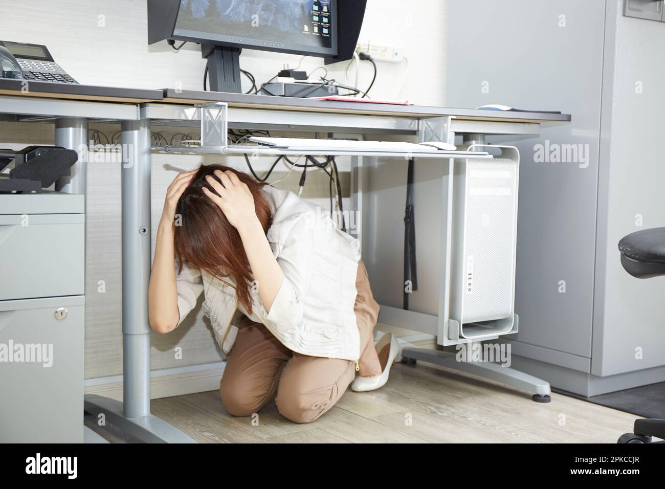 Woman hiding under desk hi-res stock photography and images - Alamy