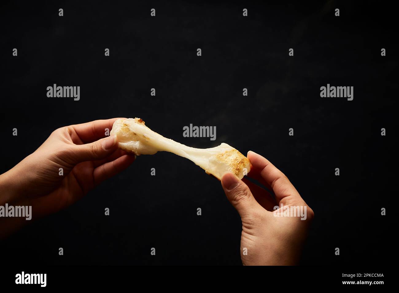 Hands breaking and stretching rice cakes on a black background Stock