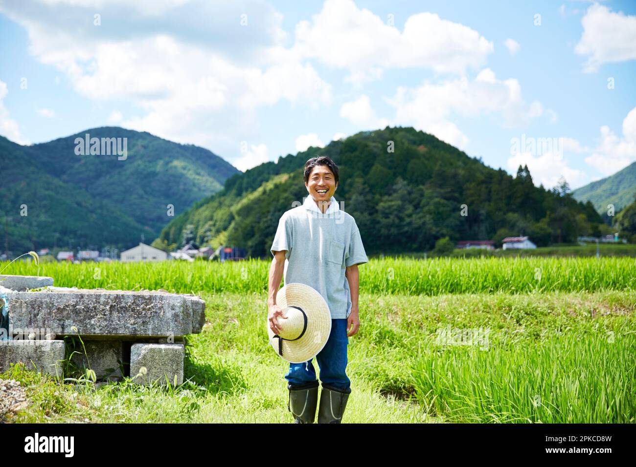 Smiling man standing between rice paddies Stock Photo