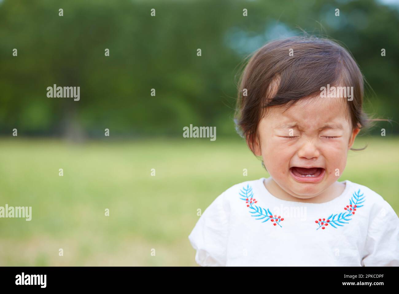 Baby crying in park Stock Photo