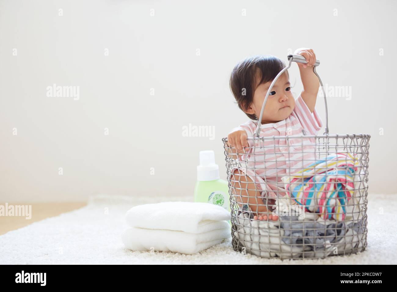 Baby in laundry basket with laundry Stock Photo