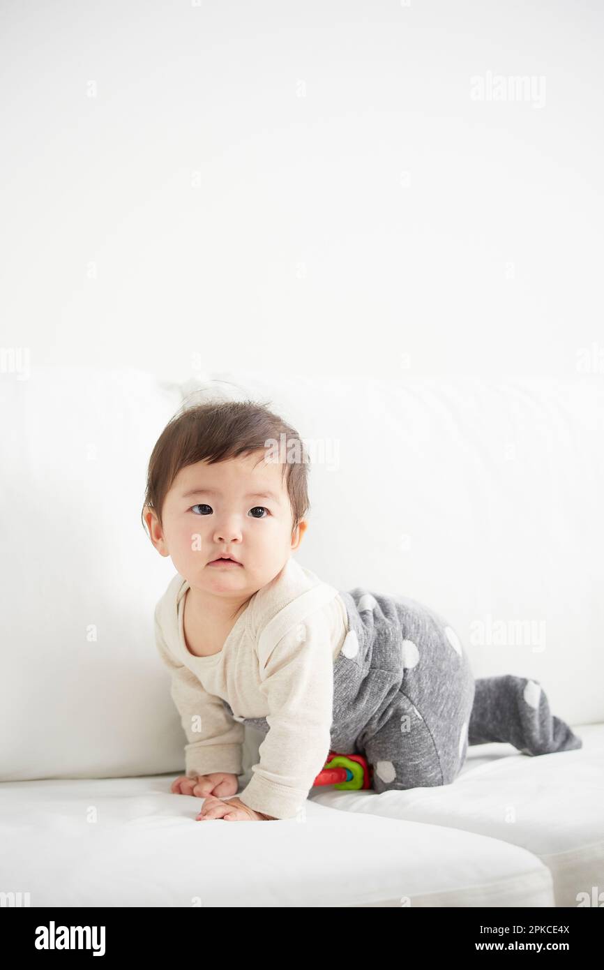Baby crawling on white sofa Stock Photo