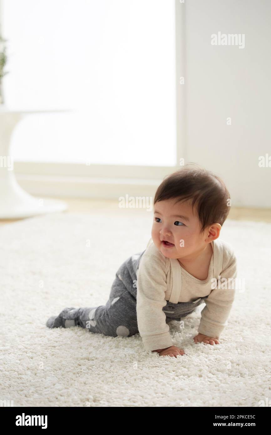 Baby crawling on white rug Stock Photo