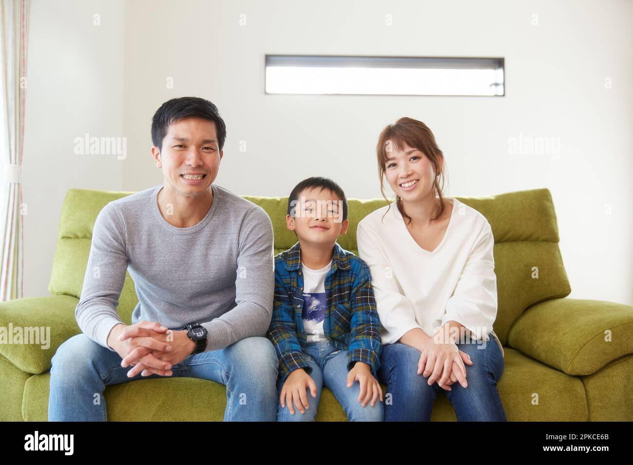 Family sitting on a sofa in the living room Stock Photo - Alamy
