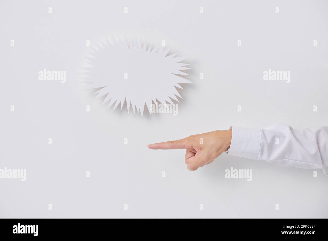 Jagged speech balloon and a person's hand pointing Stock Photo