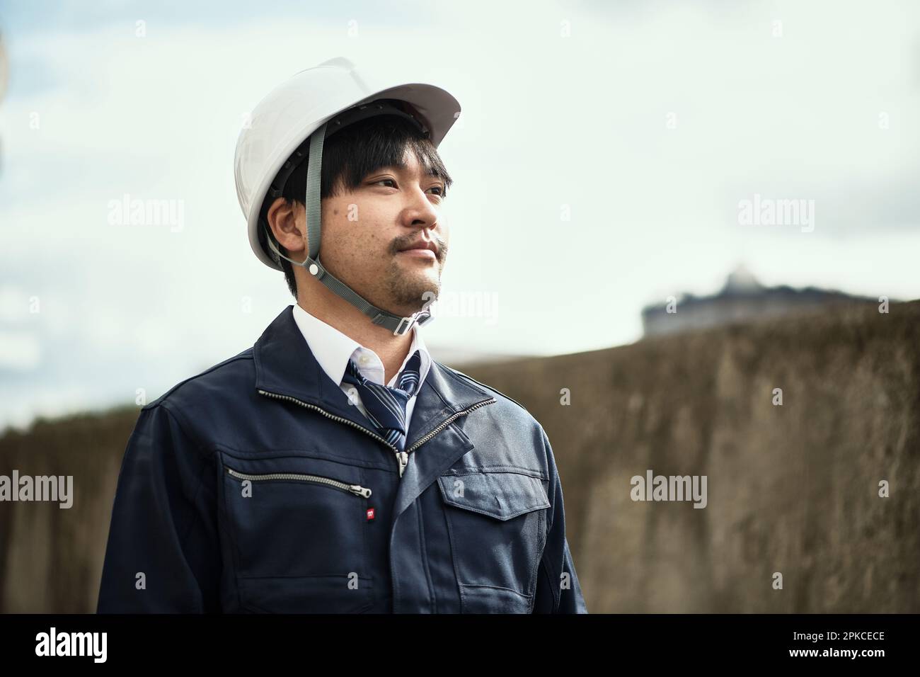 Man in work clothes and helmet looking into distance Stock Photo