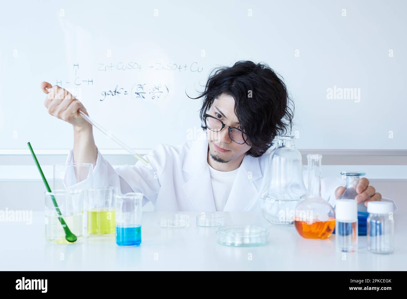 Man in lab coat experimenting with mixing colored liquid Stock Photo