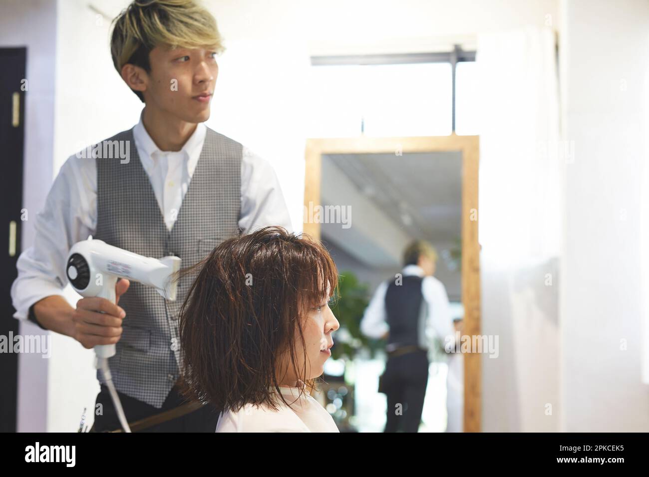 Hair stylist drying a customer's hair Stock Photo