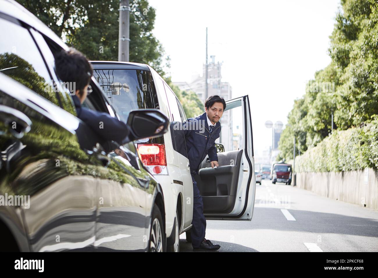 Man getting out of car and man's face out of window Stock Photo