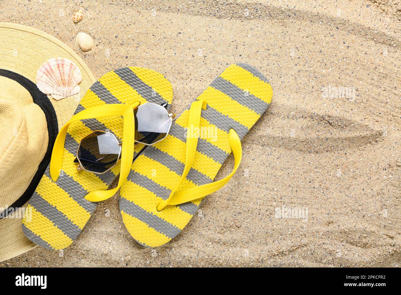 Flip-flops with sunglasses, hat and seashells on sand Stock Photo - Alamy