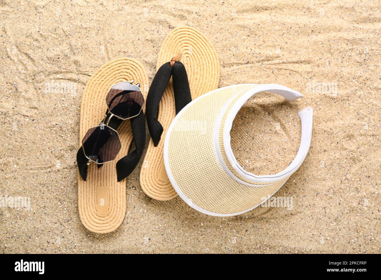 Flip-flops with sunglasses and cap on sand Stock Photo - Alamy