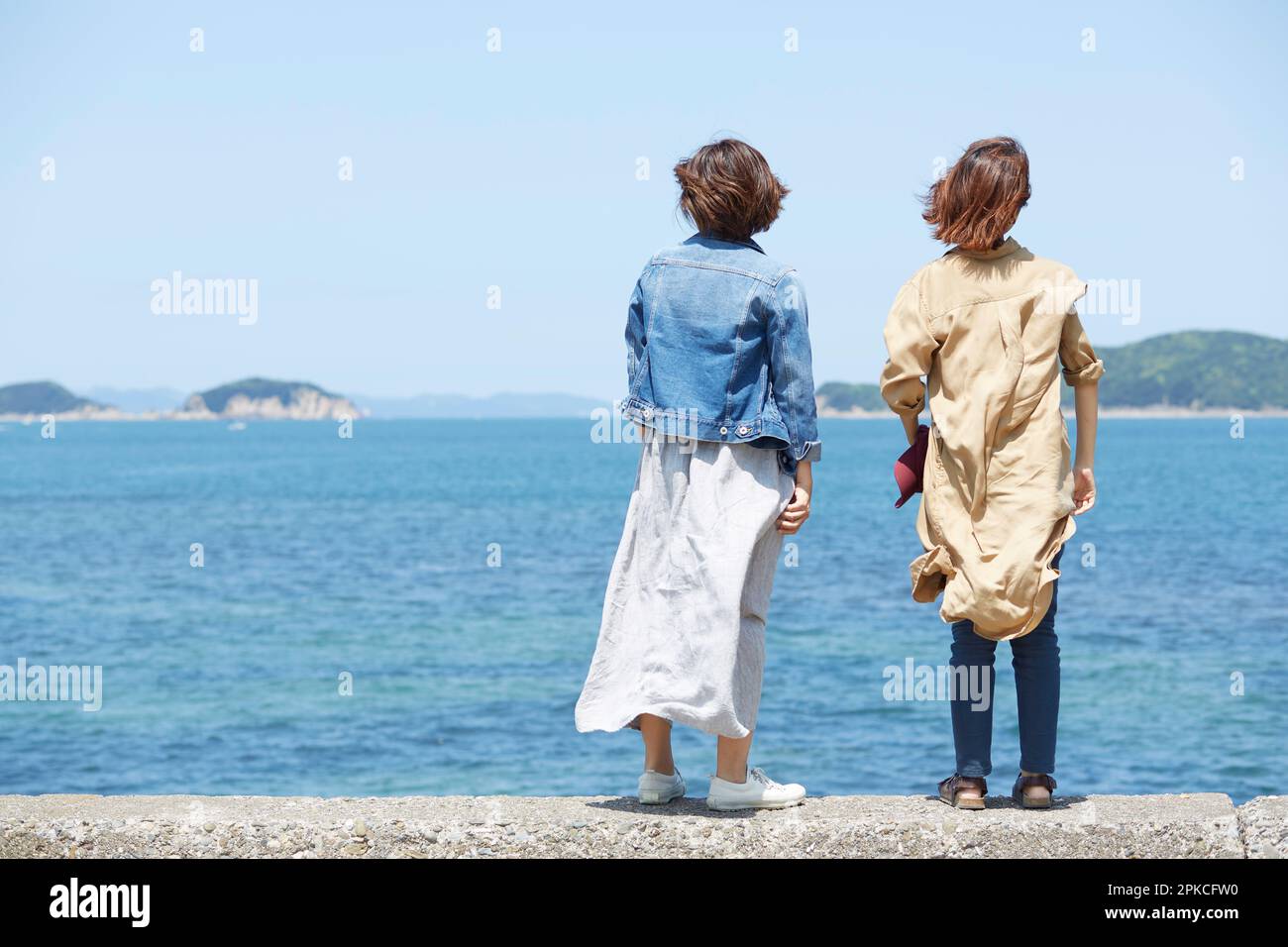 Rear view of two women looking out to sea on embankment Stock Photo