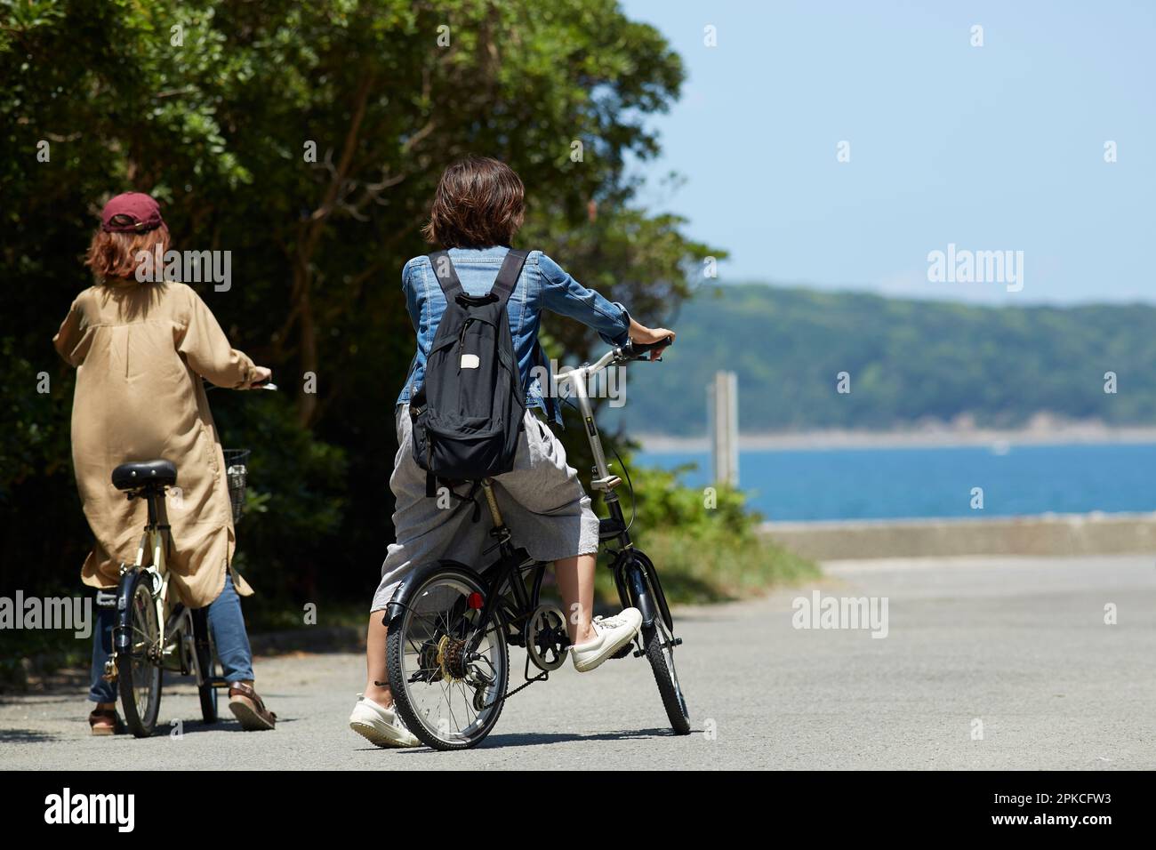 Back view of two women stopping their bicycles Stock Photo