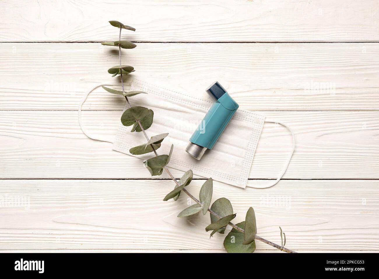 Asthma inhaler with eucalyptus branch on white wooden background Stock