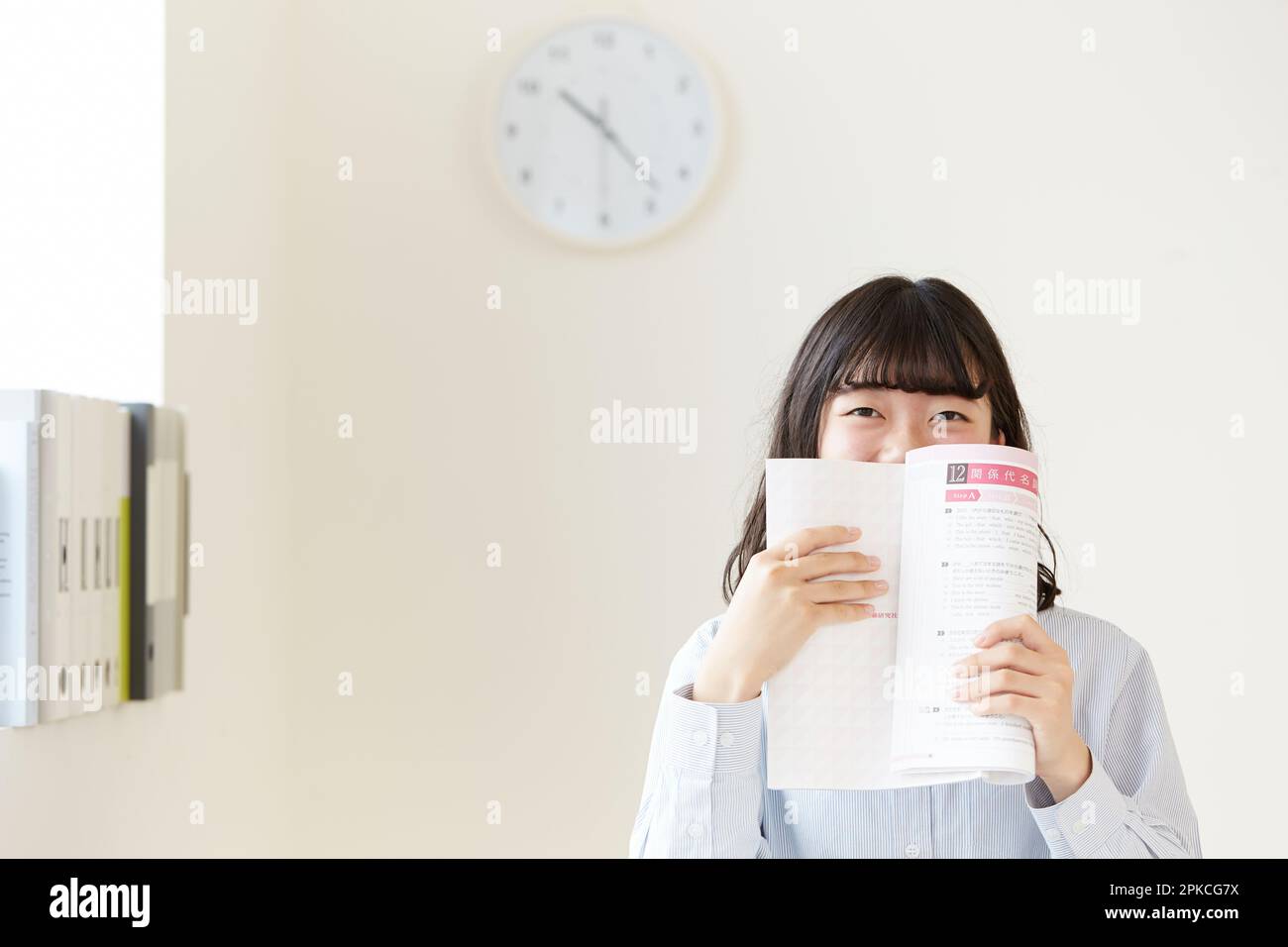High school girl laughing while covering her mouth with a reference book Stock Photo