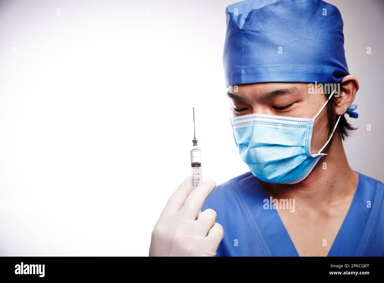 Male doctor in surgical gown holding syringe Stock Photo