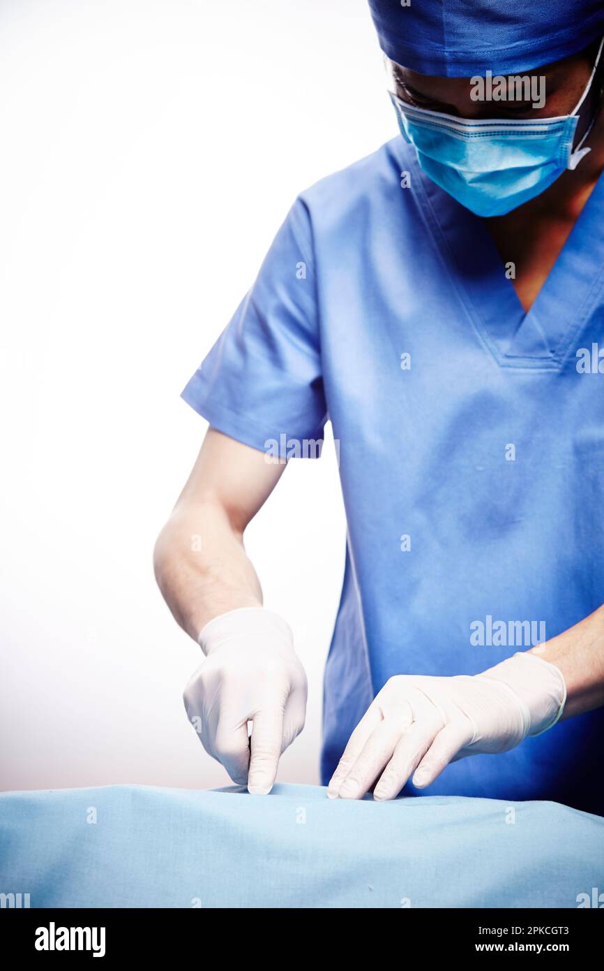 Male doctor wearing surgical gown using scalpel Stock Photo