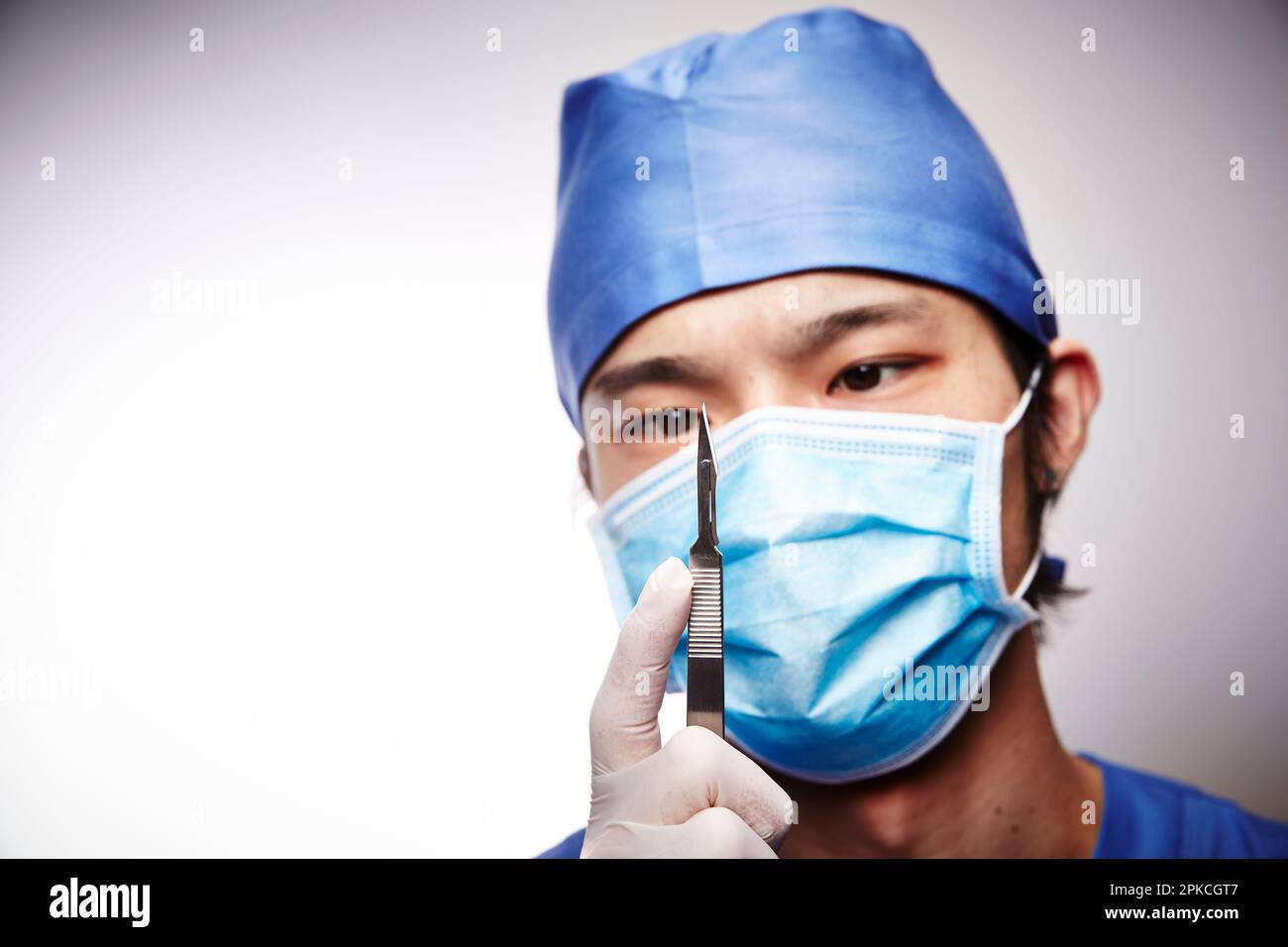 Male doctor wearing surgical gown holding scalpel Stock Photo