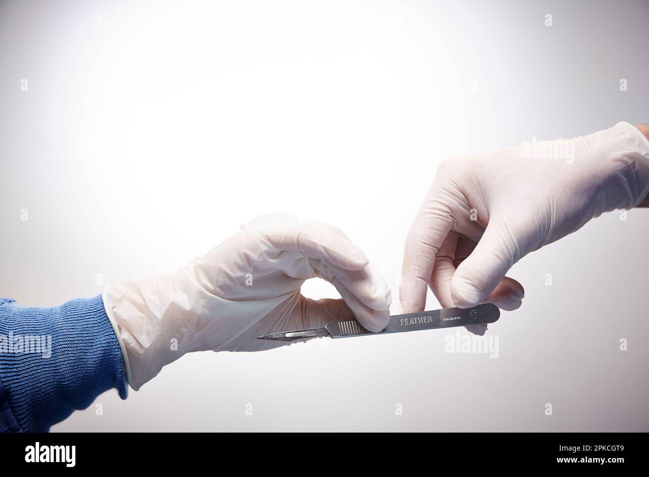 Hand handing a scalpel to a doctor in surgery Stock Photo