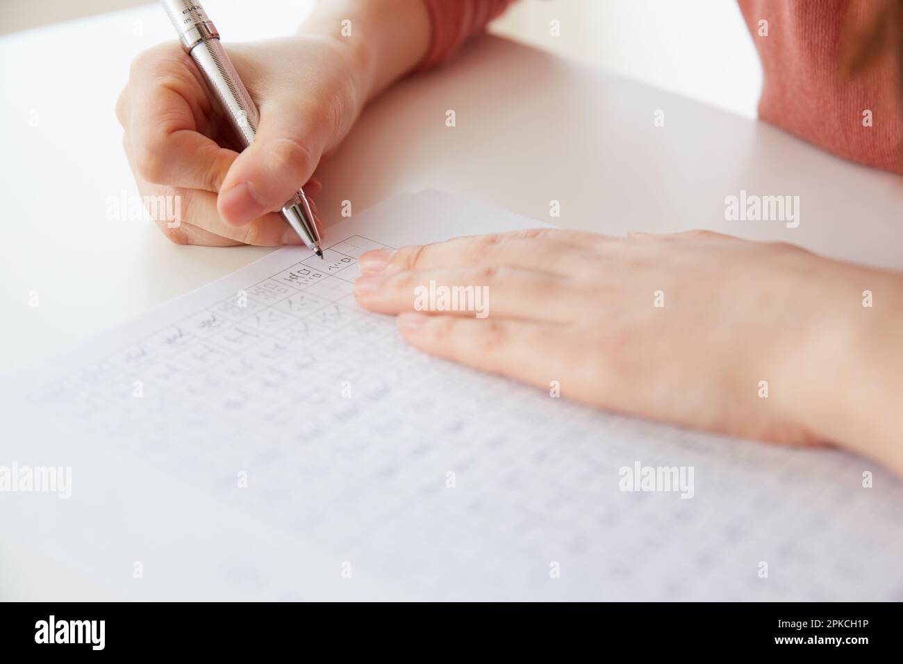 Woman's hand writing Kanji characters on white desk Stock Photo