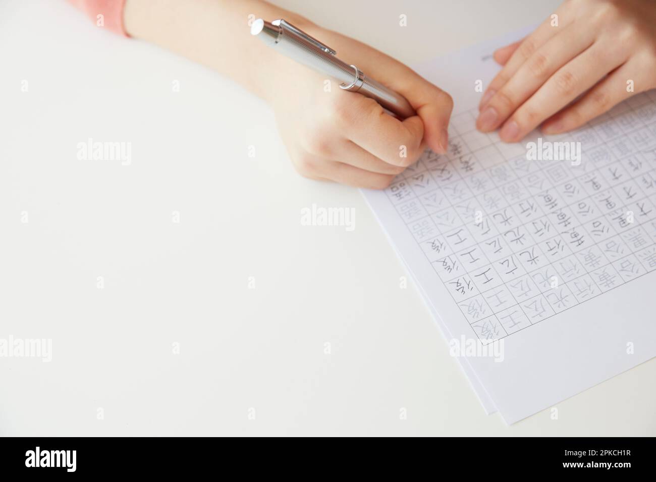 Woman writing Kanji characters on white desk Stock Photo