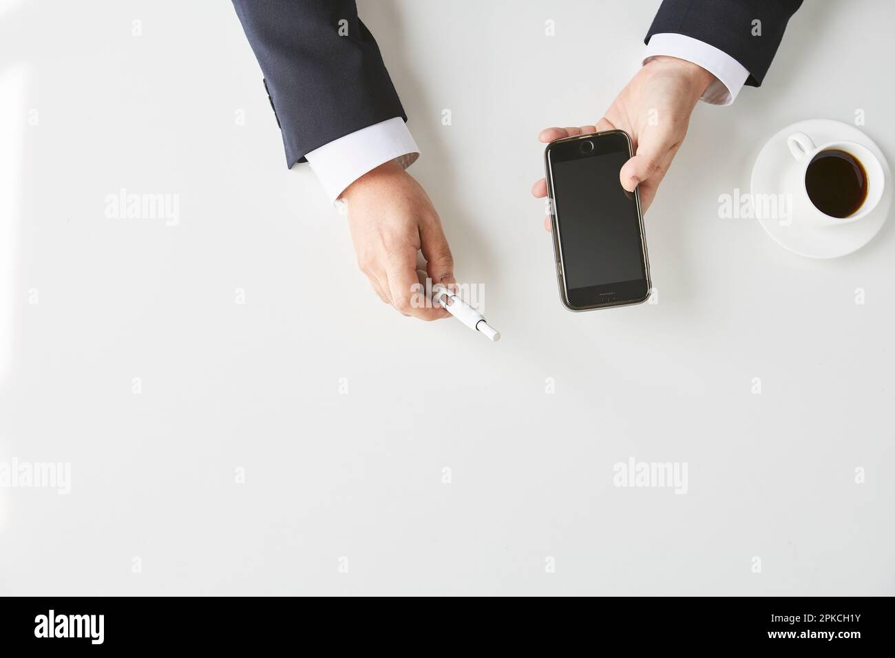 Male in suit with e-cigarette and smartphone in hand Stock Photo
