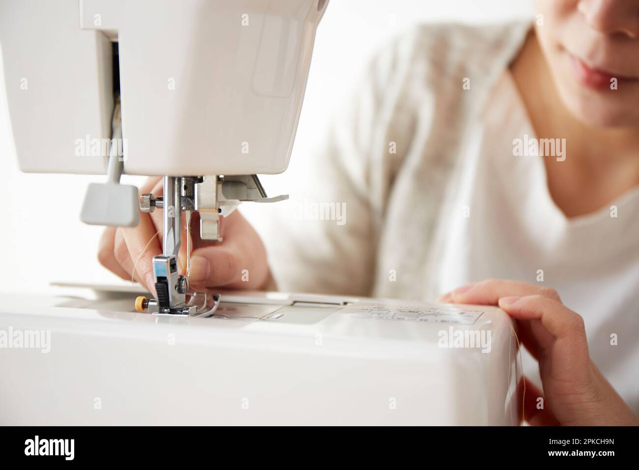A woman threading a needle on a sewing machine Stock Photo Alamy