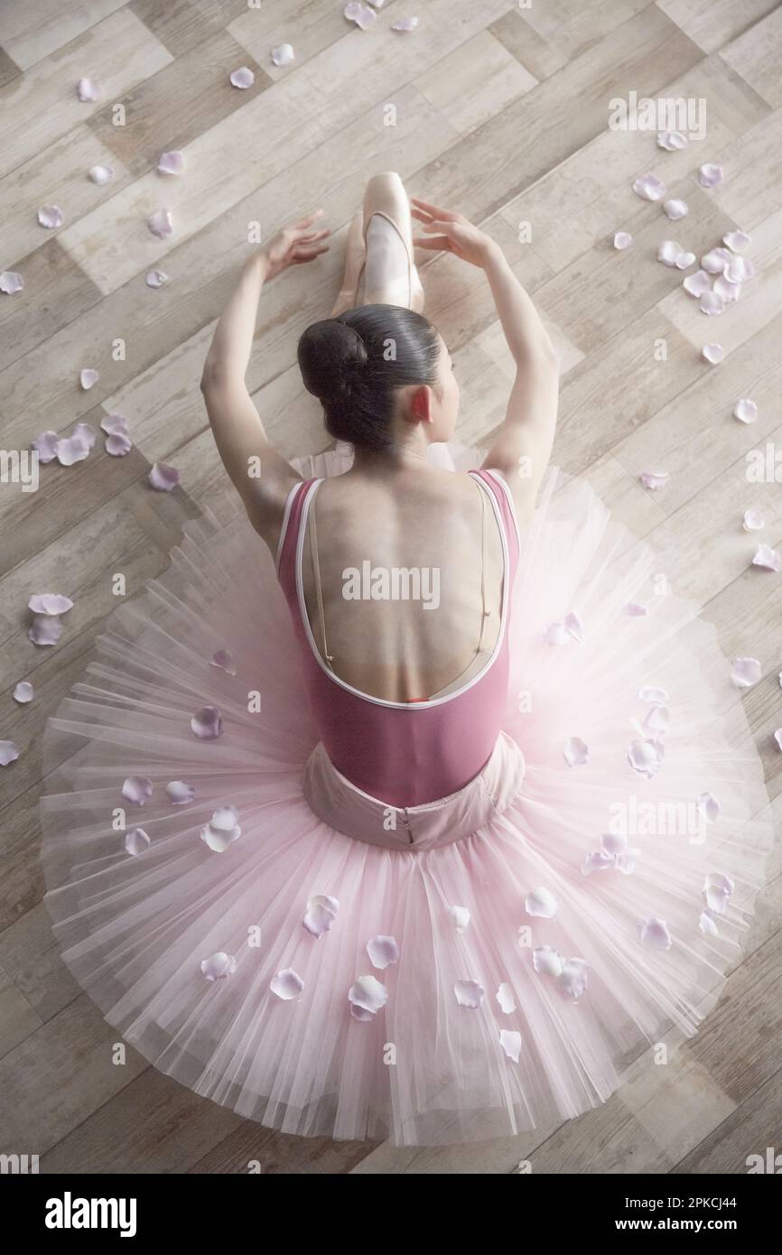 Ballerina and petal bending forward on the floor Stock Photo