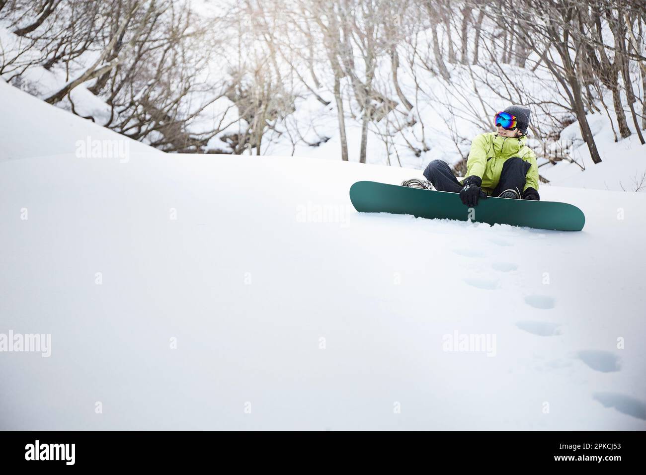 Snowboarder sitting on snow mountain Stock Photo