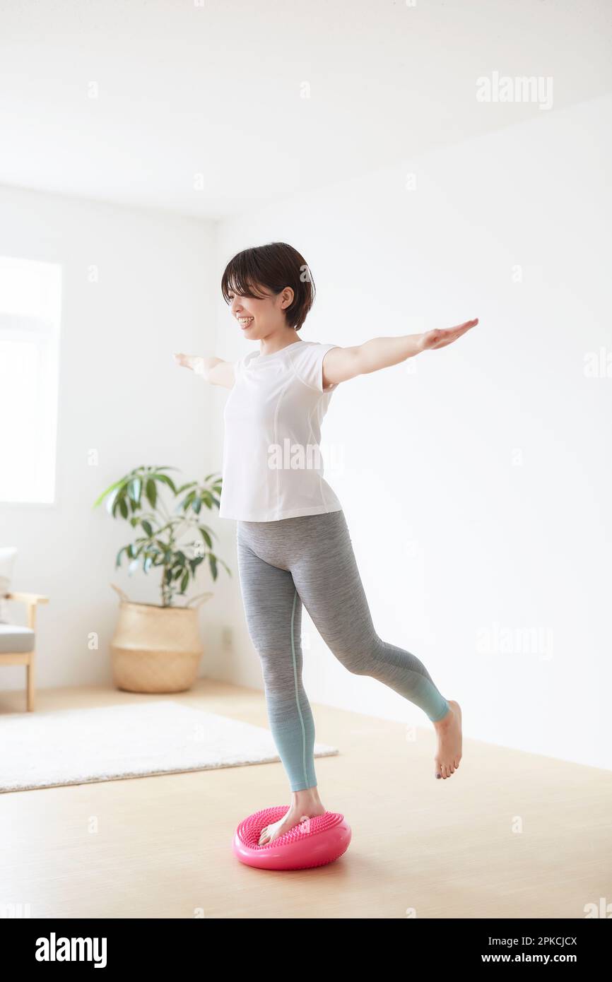 Woman working out indoors with balance disc Stock Photo