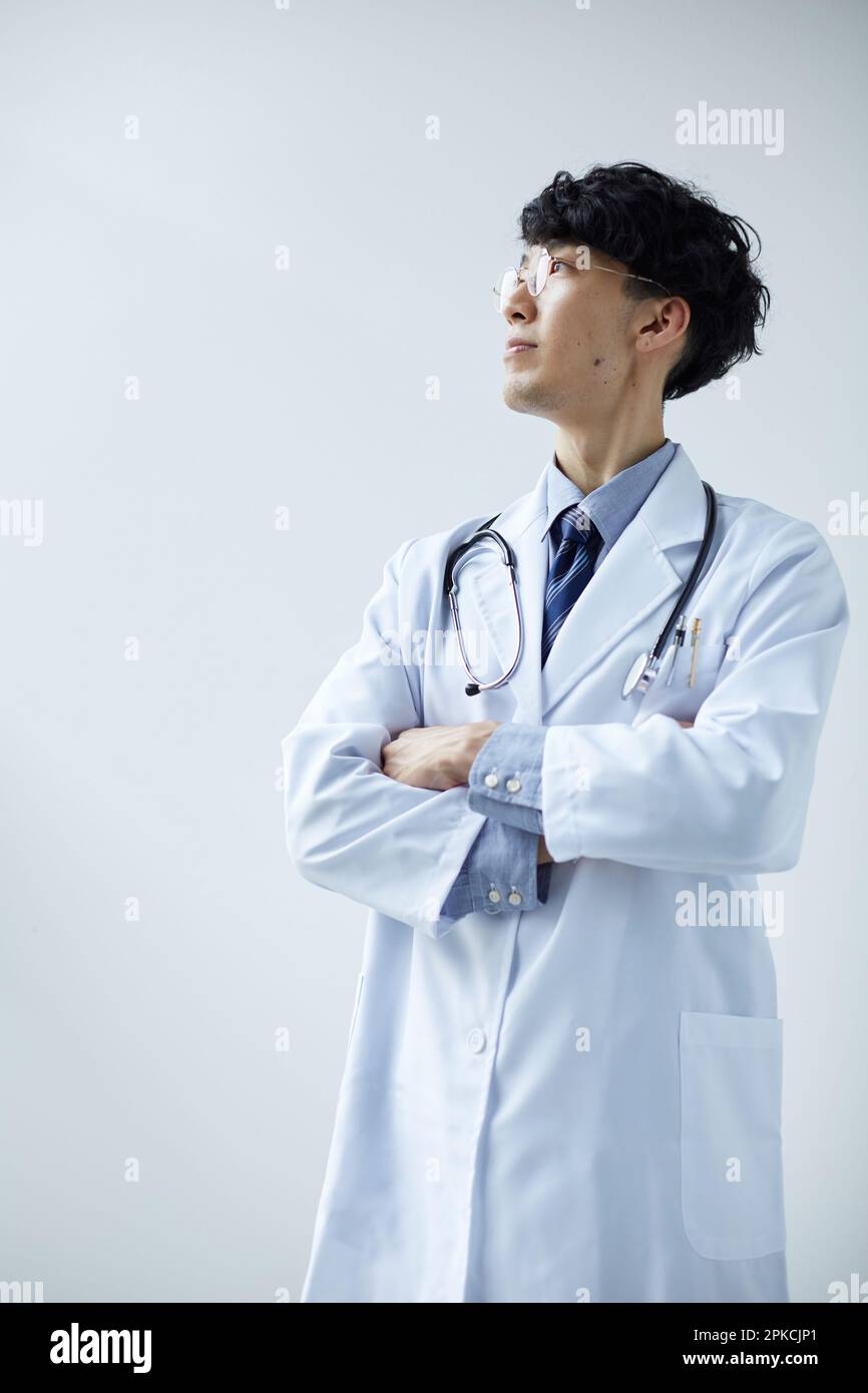 Man in white standing in front of a white wall with his arms crossed ...