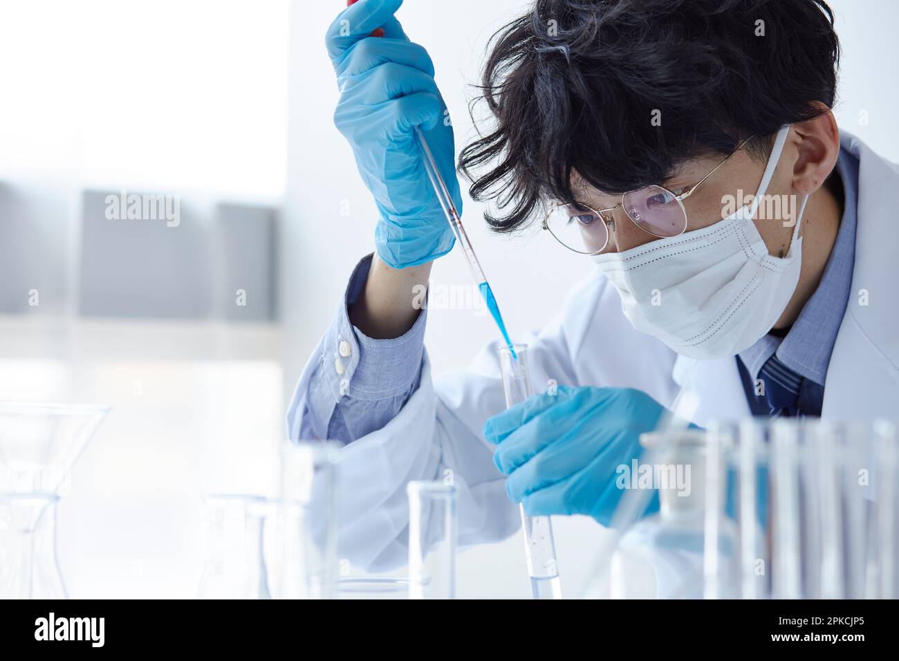 Man in lab coat experimenting in a white space Stock Photo - Alamy
