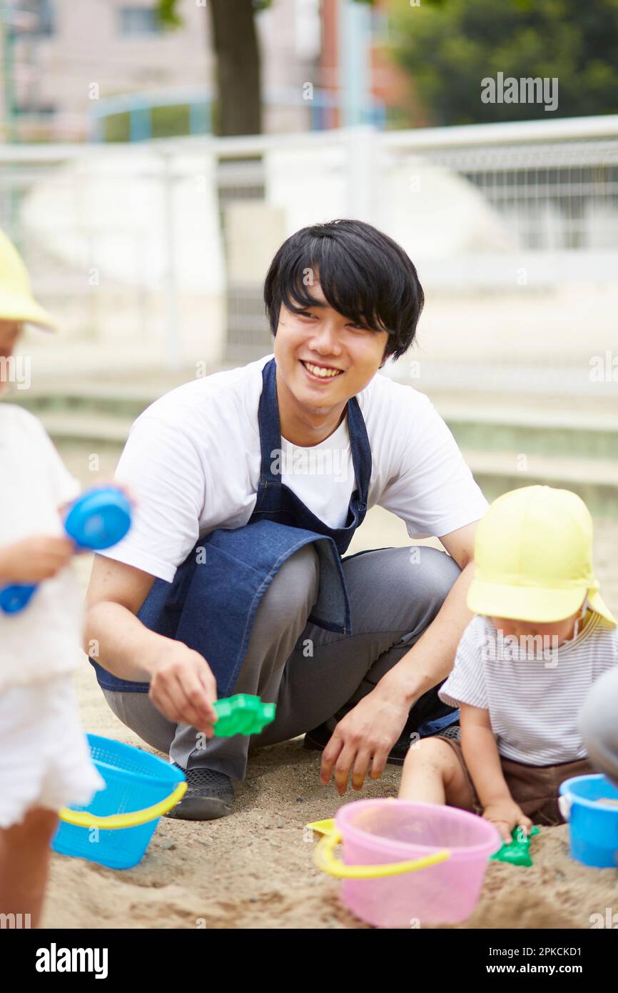 Nursery school teacher and children playing in the sandbox Stock Photo
