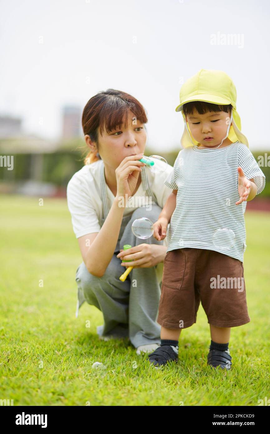 Nursery school teacher with a boy playing with soap bubbles on the lawn