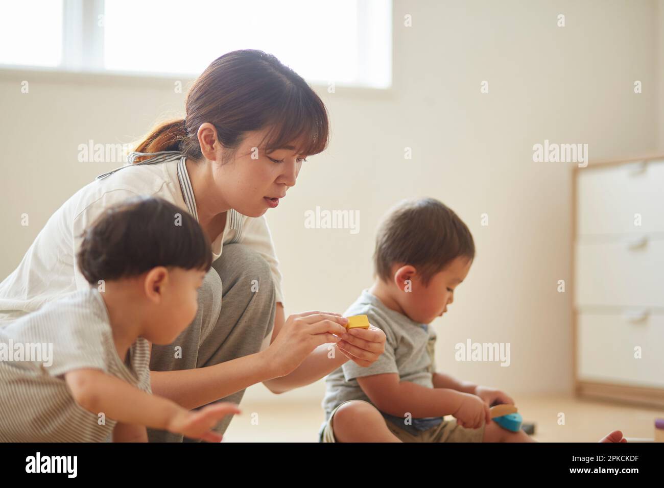 Nursery school teacher with children playing at nursery school Stock