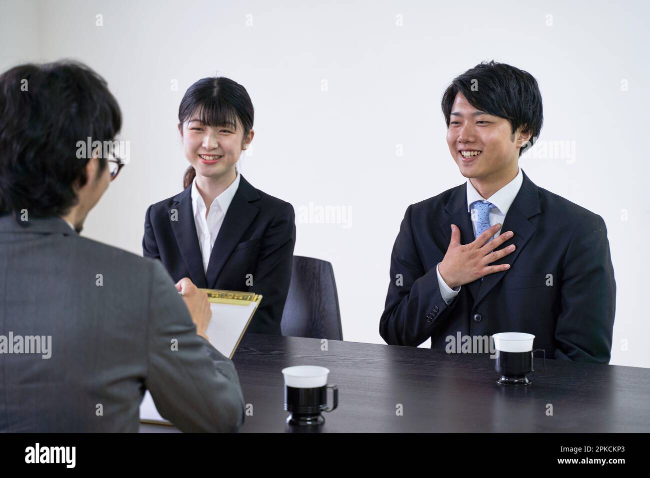 A male job hunter converses with his interviewer during a group interview. Stock Photo