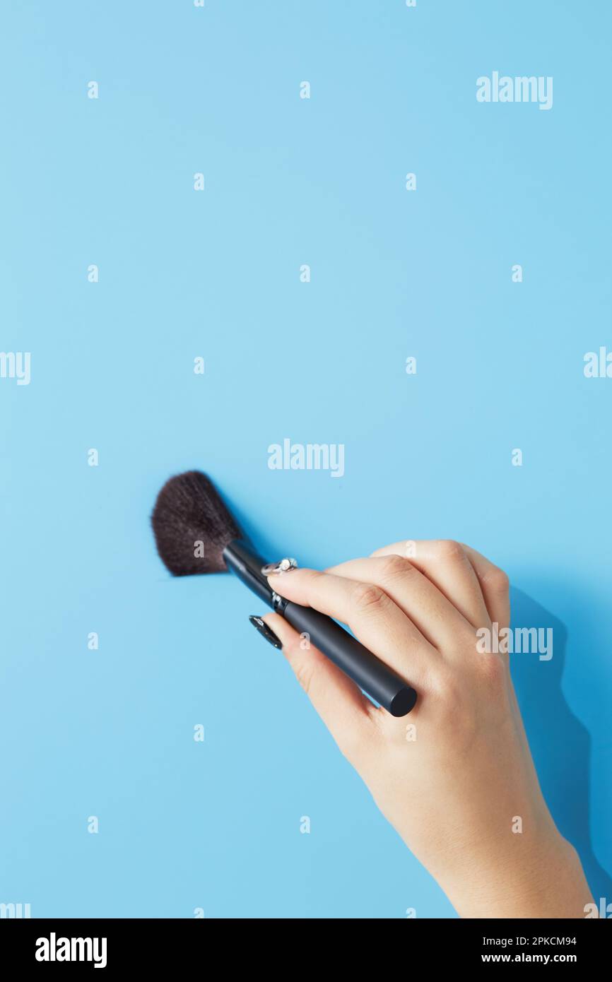 Woman's hand with powder brush on light blue background Stock Photo - Alamy