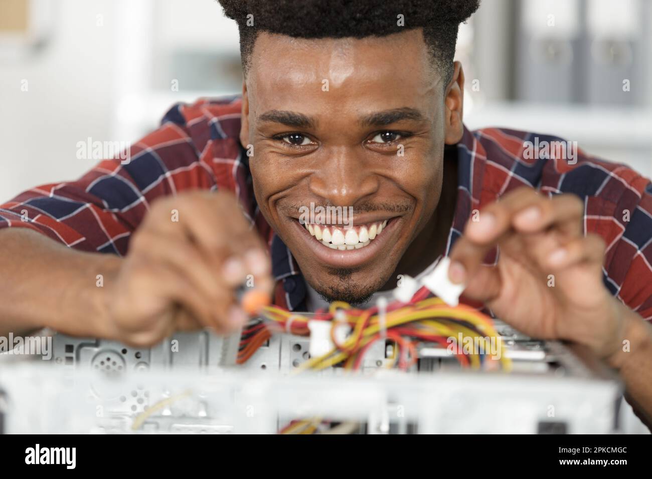 smiling man using multimeter while fixing pc Stock Photo
