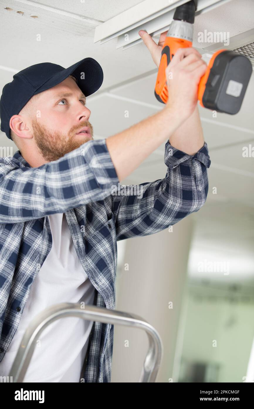 a young worker drilling ceiling Stock Photo