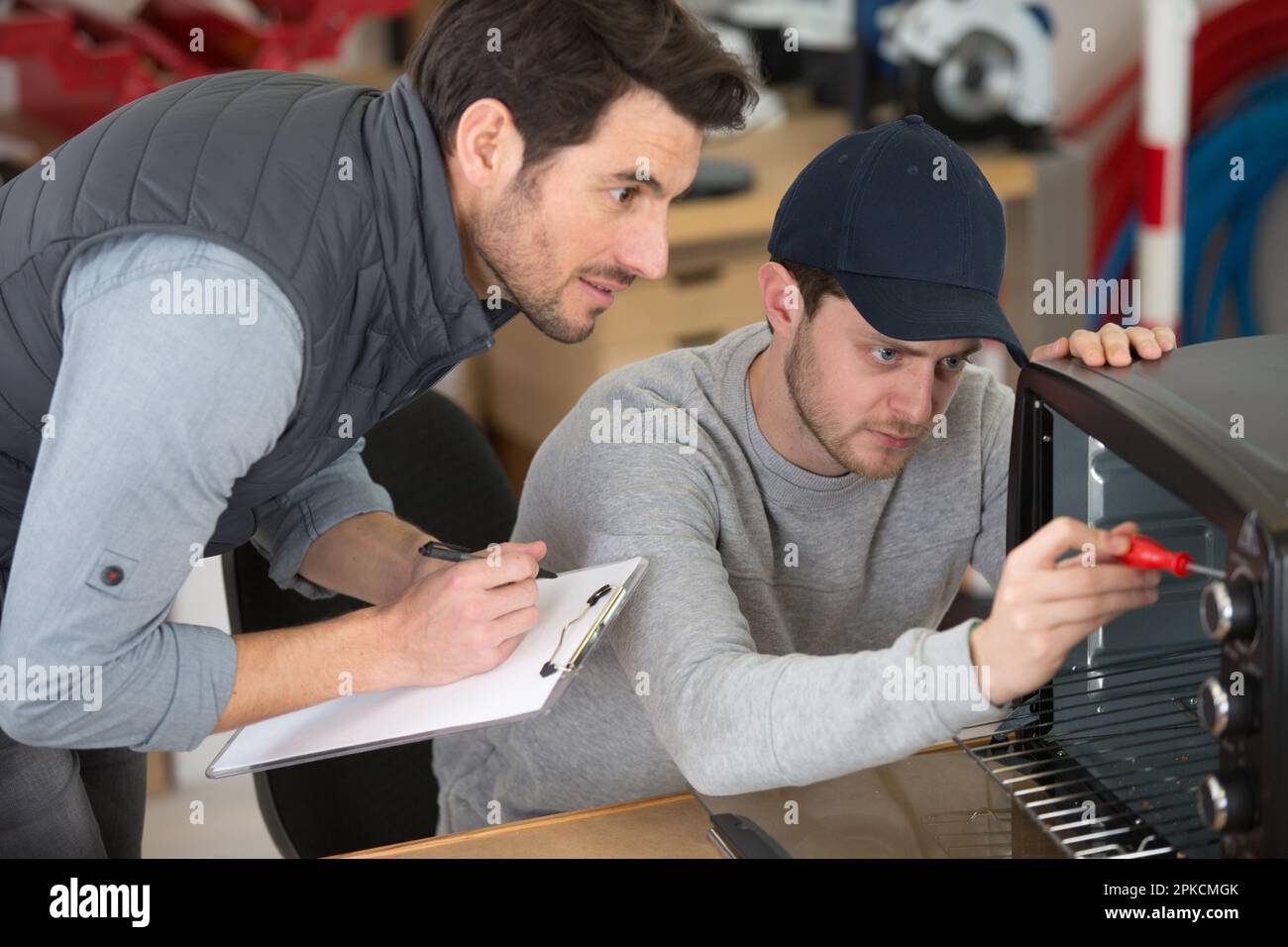 apprentice repairing an appliance under supervision Stock Photo - Alamy
