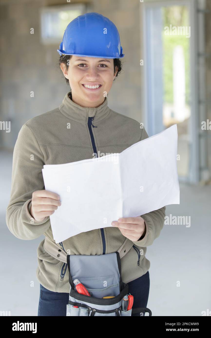female engineer looking at blueprints in construction site Stock Photo