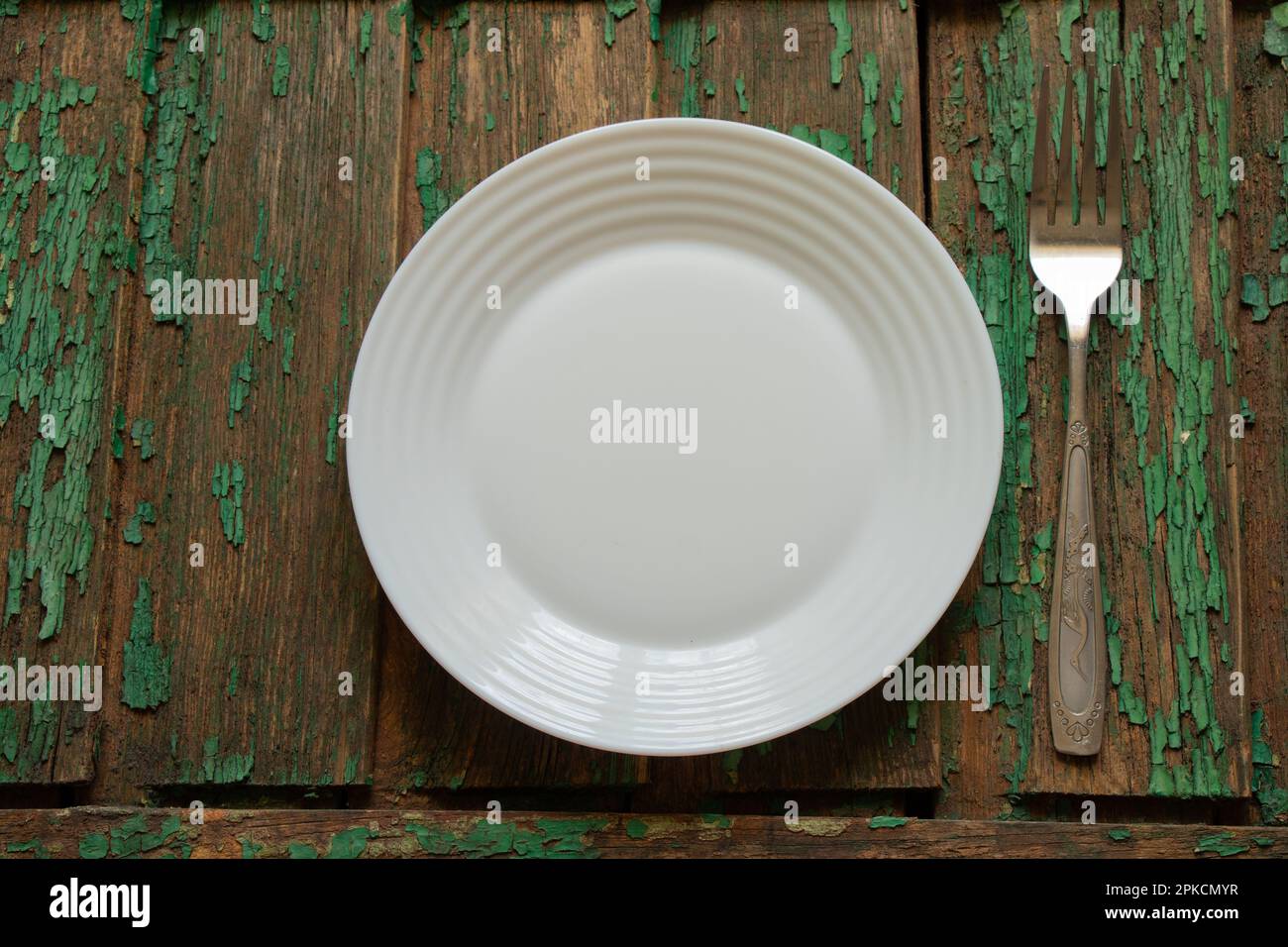 white clean empty plate and fork on wooden table Stock Photo